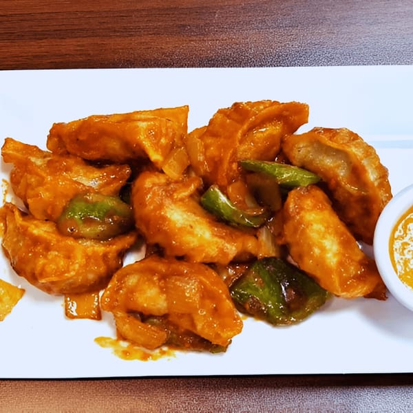 Everest Indian Kitchen's chili momos, fried dumplings with green peppers and onions, served with sauce.