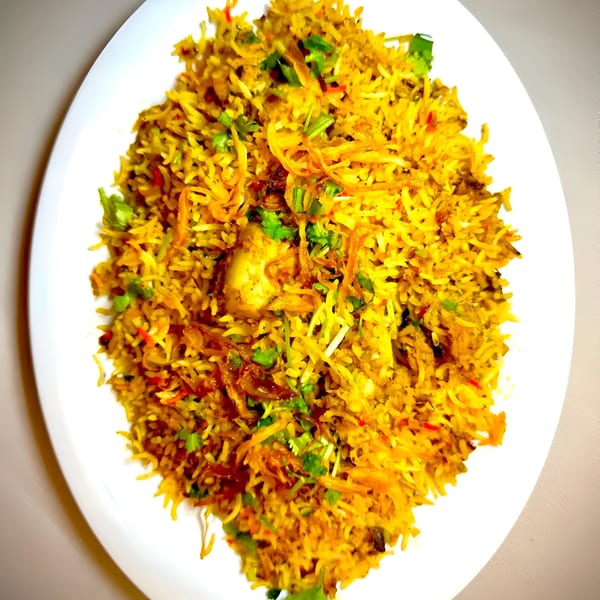A large serving of Everest Indian Kitchen's chicken biryani, garnished with fried onions and cilantro.